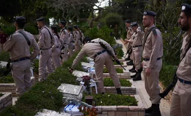 Israeli soldiers place flags and flowers on graves at a military cemetery ahead of the annual Memorial Day honoring fallen soldiers and victims of nationalistic attacks in Tel Aviv, Israel, Monday, April 20, 2026. (AP Photo/Oded Balilty)