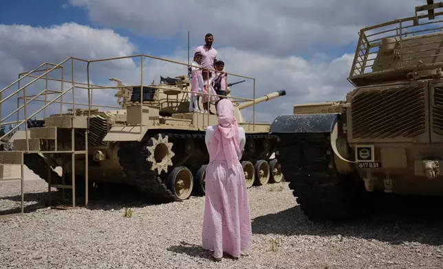 People take their photos on old tanks at the Armored Corps memorial site during a ceremony marking Israel's annual Memorial Day for the soldiers who died in the nation's conflicts and victims of nationalistic attacks, in Latrun, Israel, Tuesday, April 21, 2026. (AP Photo/Ariel Schalit)