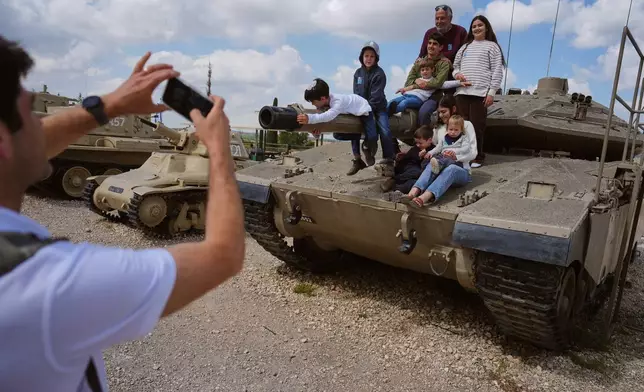 People take their photos on old tanks at the Armored Corps memorial site during a ceremony marking Israel's annual Memorial Day for the soldiers who died in the nation's conflicts and victims of nationalistic attacks, in Latrun, Israel, Tuesday, April 21, 2026. (AP Photo/Ariel Schalit)