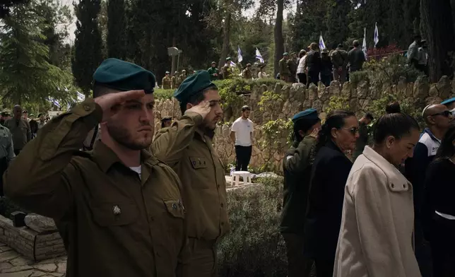 People stand still to observe two minutes of silence as air raid sirens sound, marking Israel's annual Memorial Day for the soldiers who died in the nation's conflicts and victims of nationalistic attacks at Mount Herzl military cemetery in Jerusalem, Tuesday, April 21, 2026. (AP Photo/Leo Correa)