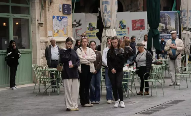 People stand still to observe two minutes of silence as air raid sirens sound, marking Israel's annual Memorial Day for the soldiers who died in the nation's conflicts and victims of nationalistic attacks, in Jerusalem, Tuesday, April 21, 2026. (AP Photo/Mahmoud illean)
