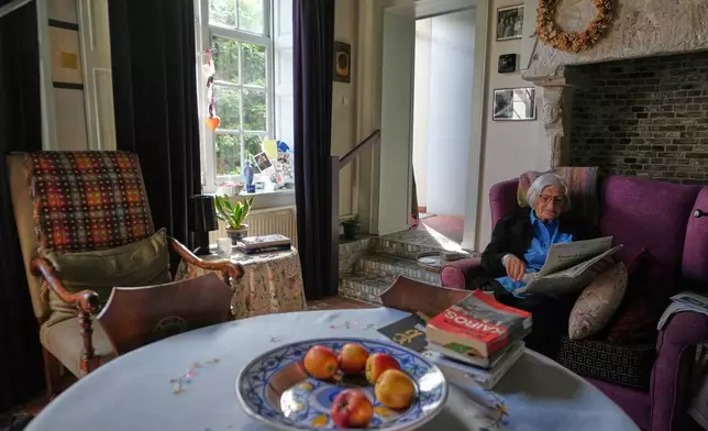 Resident Brigitte Beernaert reads a newspaper inside a house of the Beguinage Ten Wijngaerde in Bruges, Belgium, Wednesday, April 15, 2026. (AP Photo/Virginia Mayo)