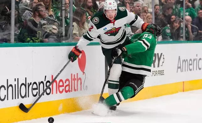 Minnesota Wild left wing Matt Boldy (12) and Dallas Stars center Wyatt Johnston (53) slam into the boards chasing after the puck in the first period of an NHL hockey game Thursday, April 9, 2026, in Arlington, Texas. (AP Photo/Tony Gutierrez)