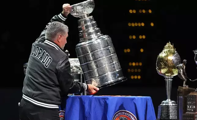 FILE - Retired NHL player Ray Bourque places the Stanley Cup on a table during a ceremony to honor members of the Colorado Avalanche's 2001 championship team that featured Bourque before an NHL hockey game against the Philadelphia Flyers, Jan. 23, 2026, in Denver. (AP Photo/David Zalubowski, File)