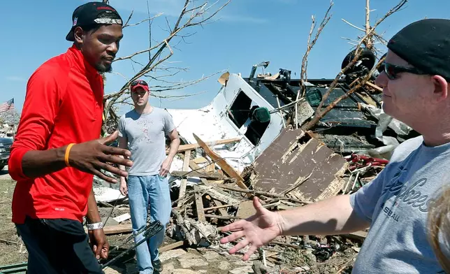 FILE - Oklahoma City Thunder NBA basketball player Kevin Durant greets Tim Kraeger, right, at his tornado-damaged home in Moore, Okla., Wednesday, May 22, 2013. Kraeger is a police officer who Durant knows from his work at the Thunder games. Durant donated $1 million to the American Red Cross for relief efforts. The Thunder matched the $1 million donation. (AP Photo/Sue Ogrocki, File)