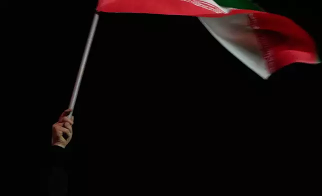 FILE - A woman chants a slogan as she waves an Iranian flag and holds a picture of the late Iranian Supreme Leader Ayatollah Ali Khamenei during a pro-government gathering in a square in western Tehran, Iran, March 25, 2026. (AP Photo/Vahid Salemi, File)