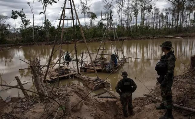 FILE - Police special forces stand next to illegal mining machinery in Peru's Tambopata province on April 1, 2019. (AP Photo/Rodrigo Abd, File)