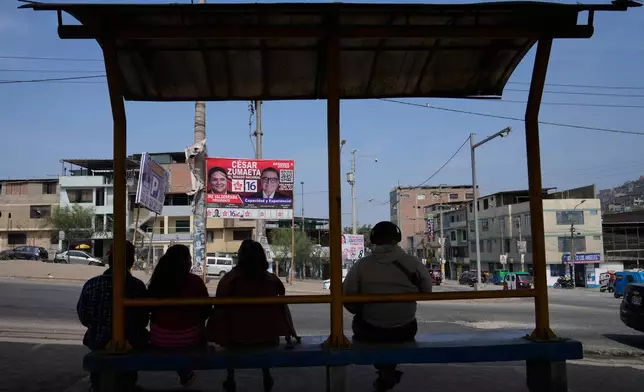 FILE - People sit in a bus station across the street from election campaign signs for presidential and congressional candidates, before the weekend's election in Lima, Peru, Friday, April 10, 2026. (AP Photo/Martin Mejia)