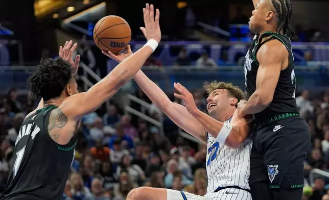 Orlando Magic forward Franz Wagner, center, shoots as he gets caught between Minnesota Timberwolves guard Terrence Shannon Jr., left, and guard Jaylen Clark during the second half of an NBA basketball game, Wednesday, April 8, 2026, in Orlando, Fla. (AP Photo/John Raoux)