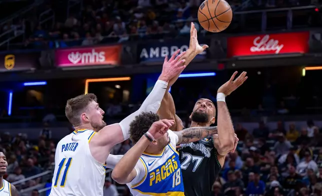 Minnesota Timberwolves center Rudy Gobert (27) battles for a rebound with Indiana Pacers center Micah Potter (11) and forward Jalen Slawson (18) during the first half of an NBA basketball game in Indianapolis, Tuesday, April 7, 2026. (AP Photo/Doug McSchooler)