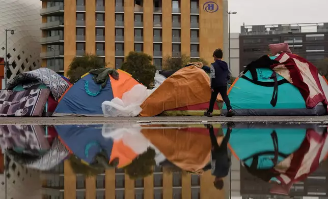 FILE — A child walks past tents sheltering people displaced by Israeli airstrikes in southern Lebanon and Dahiyeh, Beirut's southern suburbs, along the Beirut waterfront in Beirut, Lebanon, Saturday, March 14, 2026. (AP Photo/Hassan Ammar, File)
