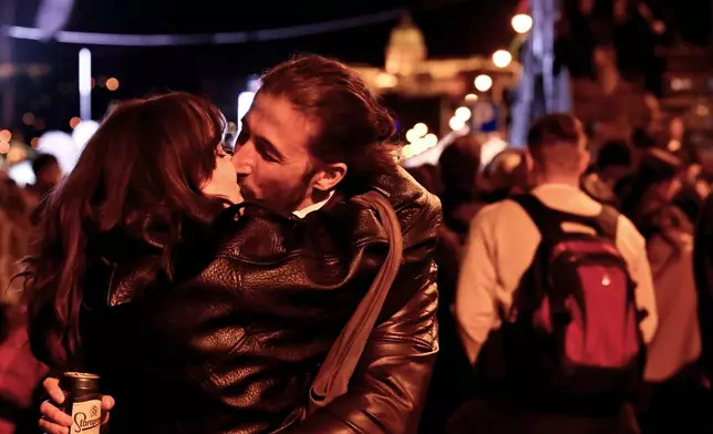 A couple kisses in the streets following the announcement of the partial results of the parliamentary election, in Budapest, Hungary, Sunday, April 12, 2026. (AP Photo/Denes Erdos)