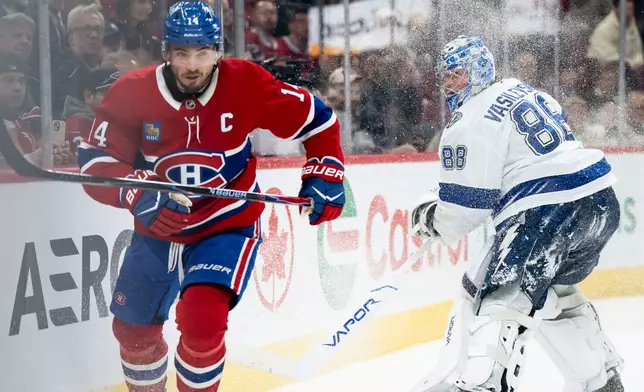 Montreal Canadiens' Nick Suzuki (14) skates towards the puck as Tampa Bay Lightning goaltender Andrei Vasilevskiy (88) clears the puck during the third period of an NHL hockey game, in Montreal, Thursday, April 9, 2026. (Christopher Katsarov/The Canadian Press via AP)