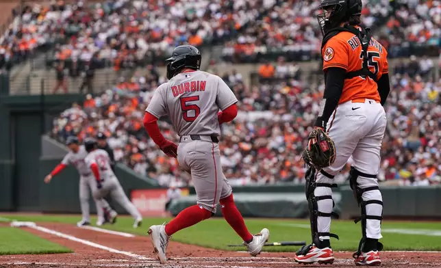Boston Red Sox' Caleb Durbin (5) scores in front of Baltimore Orioles catcher Adley Rutschman (35) on a hit by Isiah Kiner-Falefa (2) during the second inning of a baseball game, Saturday, April 25, 2026, in Baltimore. (AP Photo/Stephanie Scarbrough)