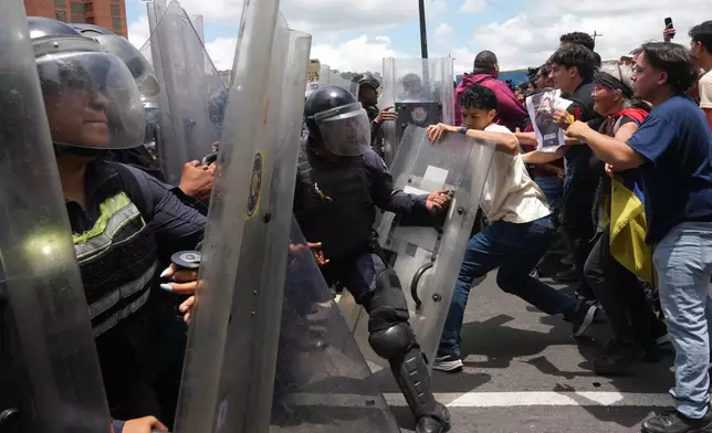 University students clash with Bolivarian National Police during a protest calling for justice after the death of Carmen Navas who died the previous day in Caracas, Venezuela, Monday, May 18, 2026, a week after the government confirmed that her missing son Victor Hugo Quero had died in custody following his arrest about a year earlier. (AP Photo/Ariana Cubillos)