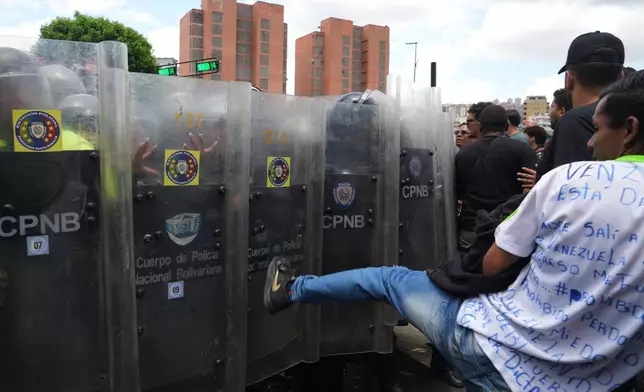University students clash with Bolivarian National Police during a protest calling for justice after the death of Carmen Navas who died the previous day in Caracas, Venezuela, Monday, May 18, 2026, a week after the government confirmed that her missing son Victor Hugo Quero had died in custody following his arrest about a year earlier. (AP Photo/Ariana Cubillos)