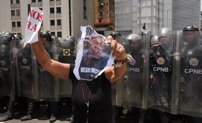 A woman holds an image of Carmen Navas during a protest calling for justice the day after her death in Caracas, Venezuela, Monday, May 18, 2026, a week after the government confirmed that her missing son Victor Hugo Quero had died in custody following his arrest about a year earlier. (AP Photo/Ariana Cubillos)
