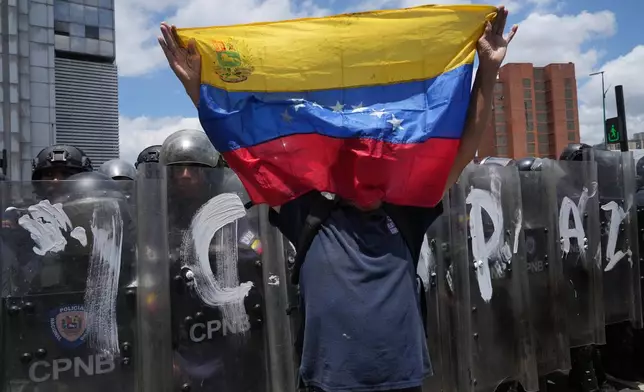 A man holds a Venezuela national flag during a protest calling for justice for Carmen Navas the day after her death in Caracas, Venezuela, Monday, May 18, 2026, a week after the government confirmed that her missing son Victor Hugo Quero had died in custody following his arrest about a year earlier. (AP Photo/Ariana Cubillos)