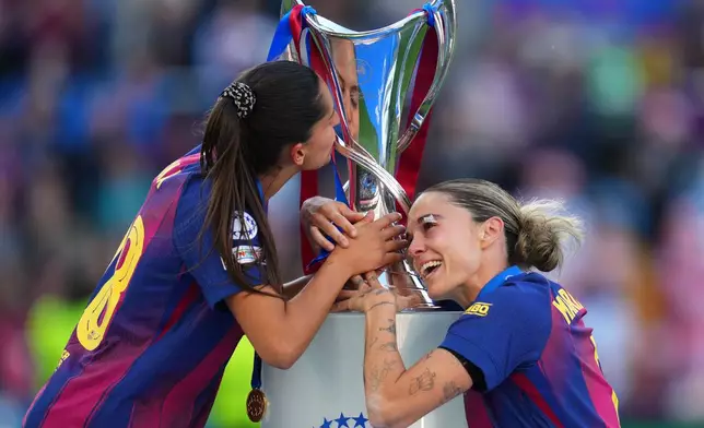 Barcelona's Kika Nazareth, left, and Mapi Leon touch the trophy after winning the Women's Champions League final soccer match between FC Barcelona and OL Lyonnes, in Oslo, Saturday, May 23, 2026. (AP Photo/Kirsty Wigglesworth)