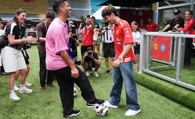 Inter Miami forward Luis Suarez, left, and Ferrari driver Charles Leclerc, of Monaco, kick a soccer ball ahead of the Miami Formula One Grand Prix auto race, Thursday, April 30, 2026, in Miami Gardens, Fla. (AP Photo/Lynne Sladky)