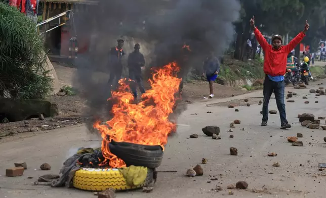 A man demonstrates near a fire during a public transport strike over fuel prices in Nairobi, Kenya, Monday, May 18, 2026. (AP Photo/Andrew Kasuku)