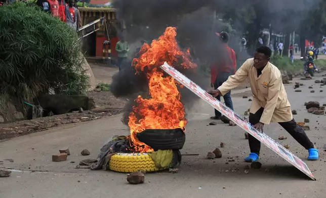 A demonstrator places a board over burning tyres during a public transport strike over fuel prices in Nairobi, Kenya, Monday, May 18, 2026. (AP Photo/Andrew Kasuku)