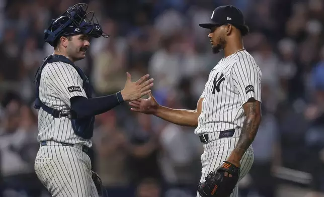 New York Yankees catcher Austin Wells, left, and pitcher Camilo Doval, right, shake hands after a win over the Toronto Blue Jays in a baseball game, Tuesday, May 19, 2026, in New York. (AP Photo/Heather Khalifa)