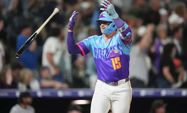 Colorado Rockies' Hunter Goodman flips his bat as he celebrates while looking back at the dugout after hitting a three-run home run off San Francisco Giants relief pitcher Caleb Kilian in the ninth inning of a baseball game Friday, May 29, 2026, in Denver. (AP Photo/David Zalubowski)