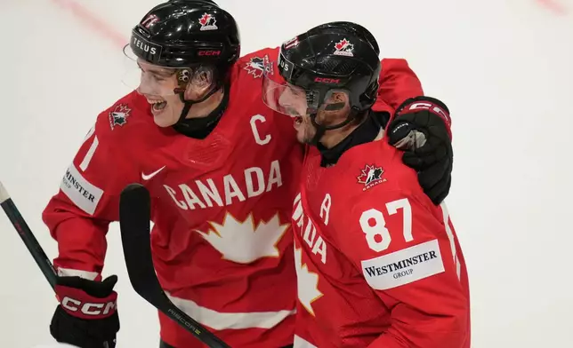Canada's Sidney Crosby (87) celebrates with Macklin Celebrini (71) after scoring a goal during the third period of the 2026 IIHF Men's Ice Hockey World Championship quarterfinal match between Canada and United States, in Fribourg, Switzerland, Thursday, May 28, 2026. (AP Photo/Darko Bandic)