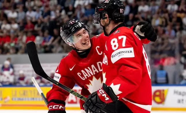 Canada's Sidney Crosby (87) celebrates with Macklin Celebrini (71) after scoring a goal during the third period of the 2026 IIHF Men's Ice Hockey World Championship quarterfinal match between Canada and United States, in Fribourg, Switzerland, Thursday, May 28, 2026. (Anthony Anex/Keystone via AP)