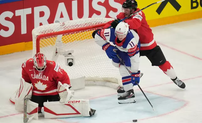 Canada goalkeeper Jet Greaves (73) and Morgan Rielly (44) defend against pressure from United States' Oliver Moore (11) during the third period of the 2026 IIHF Men's Ice Hockey World Championship quarterfinal match between Canada and United States, in Fribourg, Switzerland, Thursday, May 28, 2026. (AP Photo/Darko Bandic)