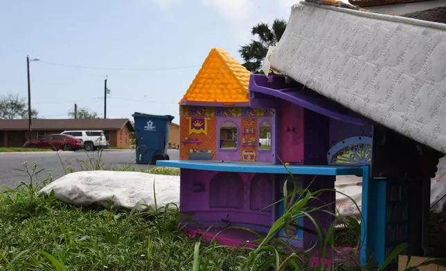 A plastic dollhouse sits among a pile of furniture discarded by families in a public housing subdivision in Port Isabel, Texas, on April 13, 2026. (AP Photo/Valerie Gonzalez)