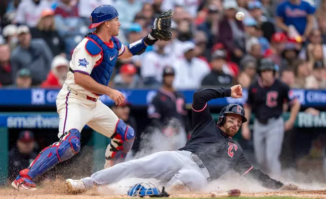 Cleveland Guardians' Daniel Schneemann, right, slides into home on a single hit by teammate Steven Kwan as Philadelphia Phillies catcher J.T. Realmuto, left, waits for the ball during the fifth inning of a baseball game, Sunday, May 24, 2026, in Philadelphia. (AP Photo/Chris Szagola)