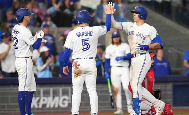 Toronto Blue Jays' Brandon Valenzuela, right, is congratulated by teammates Daulton Varsho (5) and Ernie Clement, left, as he crosses home plate after his three-run home run during fifth-inning baseball game action in Toronto, Saturday, May 9, 2026. (Chris Young/The Canadian Press via AP)