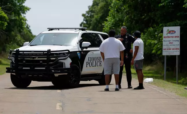 Police talks to two guys at the entrance to Scissortail Campground at Arcadia Lake in Edmond, Okla. who are wanting to get their belongings from the campground on Monday, May 4, 2026 after a party shooting on Sunday evening. (AP Photo/Alonzo Adams)