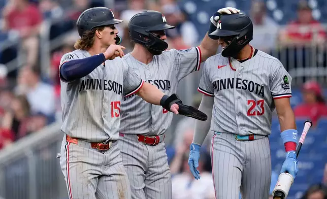 Minnesota Twins' Luke Keaschall (15) and Kody Clemens, center, celebrate with Royce Lewis (23) after scoring against the Washington Nationals on a double hit by Brooks Lee during the second inning of a baseball game, Tuesday, May 5, 2026, in Washington. (AP Photo/Jess Rapfogel)
