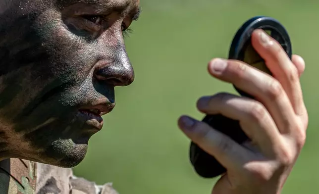 A cadet applies camouflage face paint before competing in the grenade assault course during the Sandhurst Military Skills Competition at the United States Military Academy in West Point, N.Y., Friday, May 1, 2026. (AP Photo/Julia Demaree Nikhinson)
