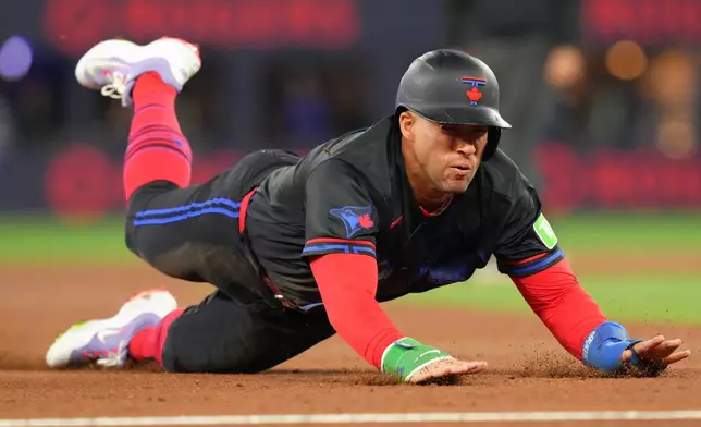 Toronto Blue Jays' George Springer (4) slides into third base against the Pittsburgh Pirates during third inning of a baseball game in Toronto, Friday, May 22, 2026. (Chris Young/The Canadian Press via AP)