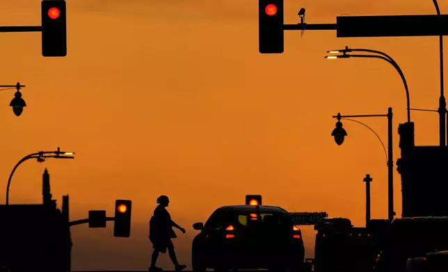 FILE - A person crosses a downtown street as the sun sets, March 31, 2025, in Kansas City, Mo. (AP Photo/Charlie Riedel, file)