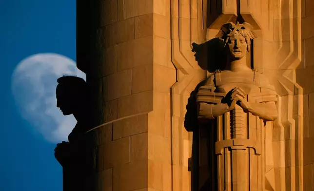 FILE - The moon rises beyond sculptures atop the Liberty Memorial tower at the National World War I Museum, July 6, 2025, in Kansas City, Mo. (AP Photo/Charlie Riedel, file)