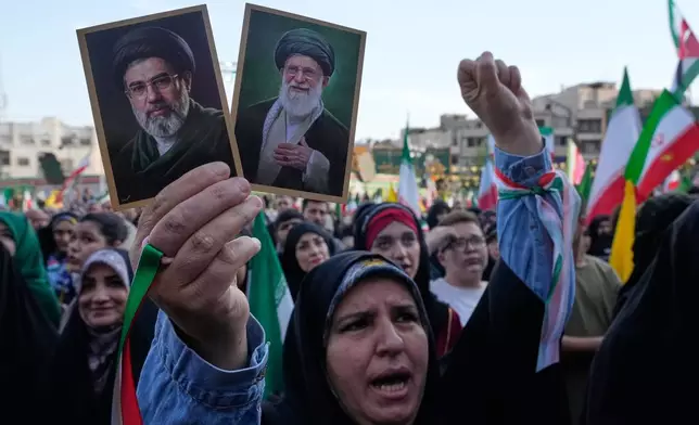 FILE - A woman holds up pictures of the Iranian Supreme Leader Ayatollah Mojtaba Khamenei, left, and his father, the slain Ayatollah Ali Khamenei, during a state-organized rally in Tehran, Iran, April 29, 2026. (AP Photo/Vahid Salemi, File)