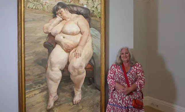 Sue Tilley, a model for British painter Lucian Freud, poses in front of Freud's painting of her, titled "Sleeping by the Lion Carpet" during an interview in Sotheby's auction house in London, Thursday, May 28, 2026. (AP Photo/Kin Cheung)