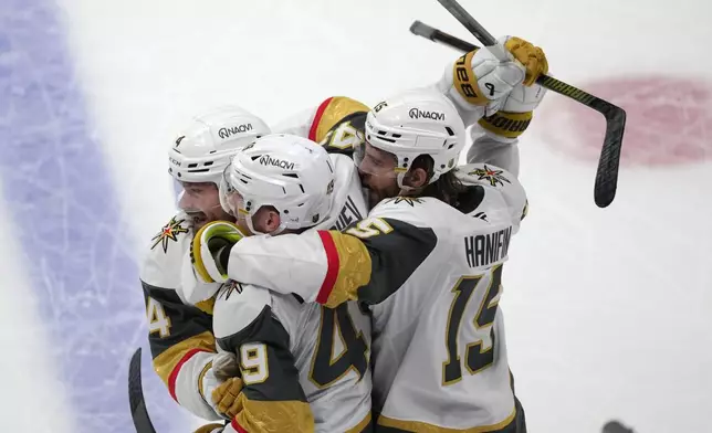 Vegas Golden Knights left wing Ivan Barbashev, center, is congratulated by Vegas Golden Knights defensemen Rasmus Andersson, left, and Noah Hanifin during the third period in Game 2 of the Western Conference finals NHL hockey Stanley Cup playoff series against the Colorado Avalanche Friday, May 22, 2026, in Denver. (AP Photo/David Zalubowski)