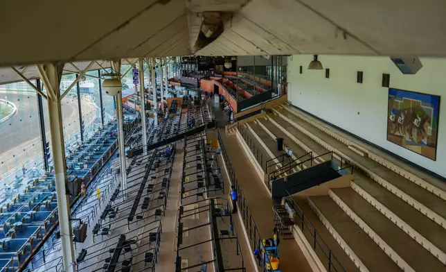 The Laurel Park grandstand sits almost empty as a janitor mops the floor during live racing, Friday, May 8, 2026, in Laurel, Md. (AP Photo/Julia Demaree Nikhinson)