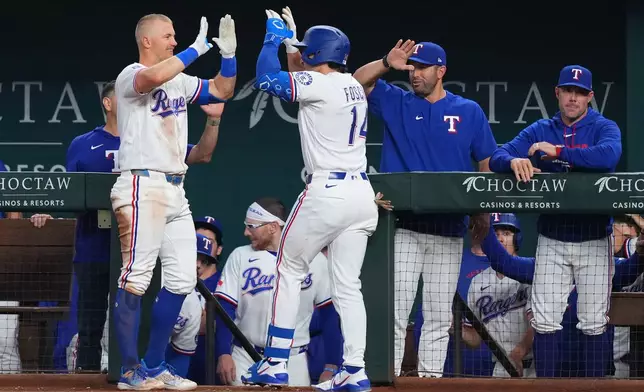 Texas Rangers' Justin Foscue, center right, is greeted by Josh Jung near the dugout after hitting his first career home run during the third inning of a baseball game against the Chicago Cubs, Saturday, May 9, 2026, in Arlington, Texas. (AP Photo/Julio Cortez)