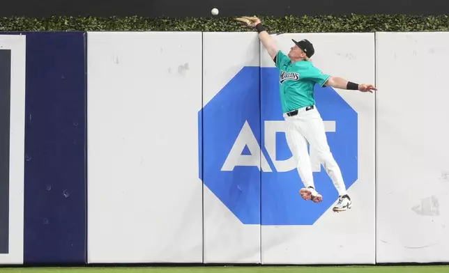 Miami Marlins right fielder Kyle Stowers attempts to catch a home run hit by Philadelphia Phillies' Bryson Stott in the first inning of a baseball game, Sunday, May 3, 2026, in Miami. (AP Photo/Jim Rassol)