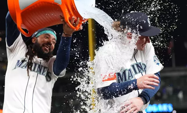 Seattle Mariners' Colt Emerson, right, is doused by teammate J.P. Crawford, left, as they celebrate a win over the Chicago White Sox after a baseball game, Monday, May 18, 2026, in Seattle. (AP Photo/Lindsey Wasson)