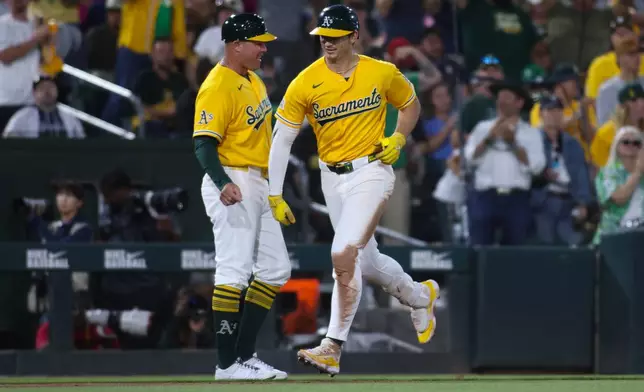 Athletics' Tyler Soderstrom, right, celebrates with third base coach Bobby Crosby, left, after hitting a solo home run during the sixth inning of a baseball game against the New York Yankees, Saturday, May 30, 2026, in West Sacramento, Calif. (AP Photo/Scott Marshall)