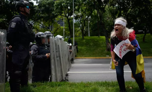 FILE - An activist screams "freedom" at Bolivarian National Police standing guard during a University student protest on a main highway in Caracas, Venezuela, May 13, 2026. (AP Photo/Ariana Cubillos, File)
