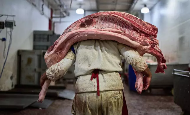 FILE - A worker carries pork inside a butcher shop at the Mataderos meat market in Buenos Aires, Argentina, May 14, 2026. (AP Photo/Rodrigo Abd, File)